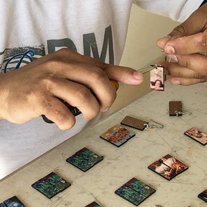 A closeup photo of hands putting on ear wires on our famous painting earrings.