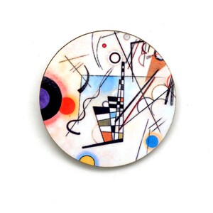 A round pin featuring the artwork of Wassily Kandinsky Composition. It has a white background with lines, circles, squiggles and arcs. The colors are blue, purple, black, red and yellow.