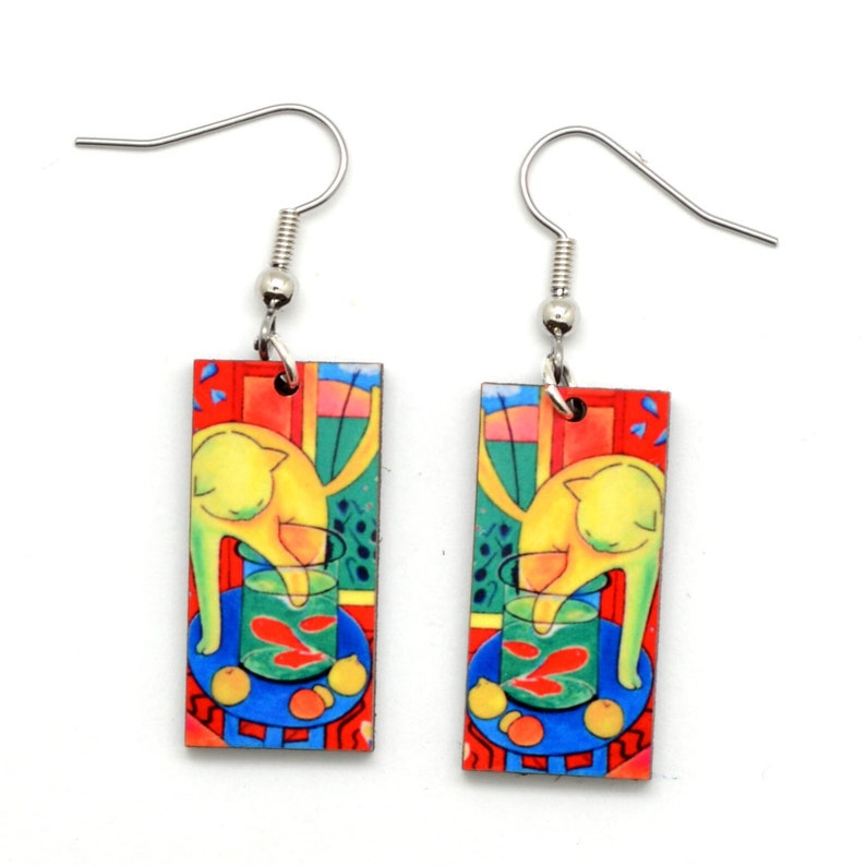 Rectangle earrings featuring the bright artwork of Matisse. There is a yellow cat with it's paw in a fish bowl with red fish. The painting has bright green, yellow, red and blue. Each rectangle shows the cat in a different direction.