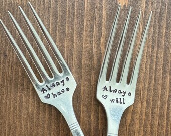 May include: Two silver forks with the words "Always have" and "Always will" engraved on them. The forks are crossed over each other.