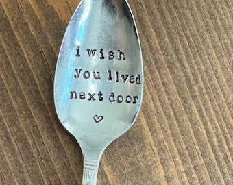 May include: A silver spoon with the words "i wish you lived next door" engraved on the front. A small heart is engraved below the text.