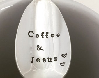 Puede incluir: Una cuchara de plata con las palabras "Coffee & Jesus" grabadas en ella, descansando en una taza de café blanca con café dentro.