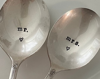 May include: Two silver spoons with engraved text, "mr." and "mrs." with a small heart symbol on each spoon.