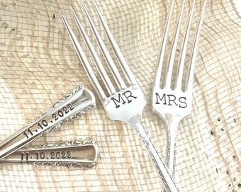May include: Two silver forks with the words "MR" and "MRS" engraved on the handles. The forks are crossed and the handles are engraved with the date "11.10.2022".