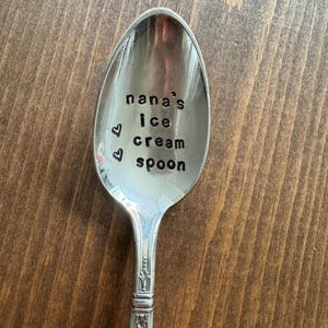 May include: A silver spoon with the words "nana's ice cream spoon" engraved on the bowl. Two small hearts are engraved above the text.