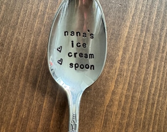 May include: A silver spoon with the words "nana's ice cream spoon" engraved on the bowl. Two small hearts are engraved above the text.