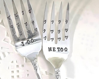 May include: Two silver forks with heart designs on the tines. One fork says "I Do" and the other says "Me Too".