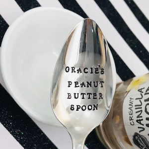 May include: A silver spoon with the words "Gracie's Peanut Butter Spoon" engraved on the front.