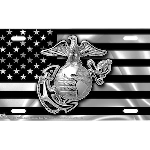 May include: A license plate featuring a black and white American flag design with the emblem of the United States Marine Corps. The emblem includes an eagle, globe, and anchor in a metallic silver color.