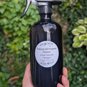 May include: A black spray bottle with a white label that reads "Natural All Purpose Cleaner Loran Naturals *Orange* Not for use on stone surfaces".