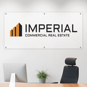 May include: A modern office interior with a wooden desk, a black office chair, and a white wall with a sign that reads "IMPERIAL COMMERCIAL REAL ESTATE".