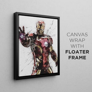 Op de afbeelding: Een zwart ingelijste canvasprint van een superheld in een rood en gouden pak met een witte achtergrond. De superheld staat met zijn arm uitgestrekt en heeft een vastberaden uitdrukking op zijn gezicht. De tekst "CANVAS WRAP WITH FLOATER FRAME" is zichtbaar in de rechterbenedenhoek van de afbeelding.