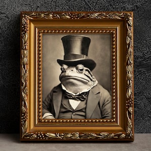 May include: A black and white vintage photograph of a toad wearing a top hat and a bow tie. The toad is sitting in a chair and has a serious expression on its face. The photograph is framed in a gold frame.