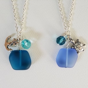 Peut inclure: Deux colliers en argent avec des pendentifs en verre bleu. L'un des colliers a un pendentif en forme d'ancre et une perle de cristal turquoise. L'autre collier a un pendentif en forme de tortue et une perle de cristal turquoise.