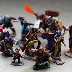 May include: A collection of painted miniature figurines depicting fantasy characters, including a warrior, a wizard, a bard, and a rogue. The figures are made of plastic and are painted in bright colors.