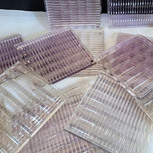 May include: A collection of clear glass tiles with a textured, ribbed pattern. The tiles are various sizes and are arranged in a random pattern.