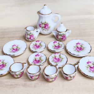 以下が含まれることがあります： バラの花柄のミニチュア磁器ティーセット。ティーポット、クリーマー、シュガーボウル、お皿、カップが含まれています。各ピースは白で、ピンクのバラと金のトリムが付いています。ドールハウスやディスプレイに最適です。