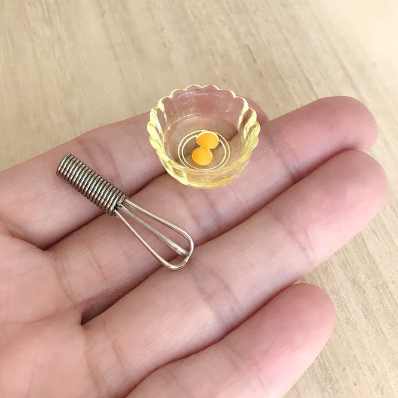 Peut inclure: Sc&egrave;ne de cuisine miniature avec un petit fouet argent&eacute; et un bol festonn&eacute; jaune contenant deux jaunes d'&oelig;ufs orange. Les articles sont probablement destin&eacute;s &agrave; une maison de poup&eacute;e ou &agrave; une collection miniature.