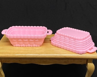 May include: Two pink plastic baskets, one with a woven design and the other with a stacked design. Both baskets are empty.