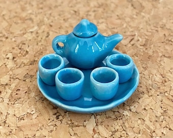 May include: A blue ceramic tea set with a teapot and four cups on a matching saucer. The set is miniature in size.