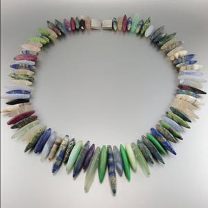 May include: A colorful necklace made of various semi-precious stones, each bead is a different shape and color, with a silver clasp.