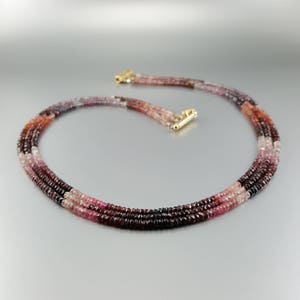 Peut inclure: Un collier multi-rangs composé de perles de pierres précieuses roses, rouges et violettes. Le collier est composé de trois rangs de perles, chaque rang étant d'une couleur différente. Le collier est composé de petites perles rondes.