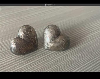 May include: A pair of silver heart-shaped earrings with an intricate floral design.