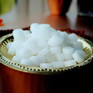 May include: A bowl filled with white camphor tablets. The bowl is made of gold metal and has a decorative design.