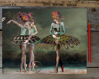 May include: Two figures in green and blue dresses with floral headpieces and butterfly wings stand on a stage. One figure holds a playing card and the other holds a glass of wine. A small red tricycle is in the foreground.