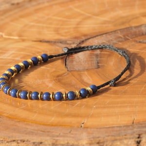 May include: A blue and gold beaded bracelet with a black cord.