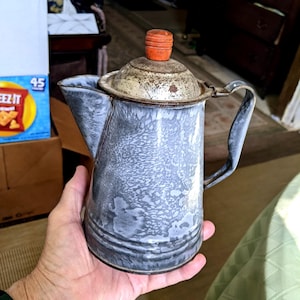 Cafeteira de granito cinza de 20 cm (8") dos anos 1920-40. Sem furos ou amassados, tudo original, inclusive o puxador vermelho da tampa. Apresenta sinais de uso em fogo aberto. INV#1128