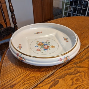 May include: A white ceramic serving bowl with a gold rim and a floral design. The bowl is divided into three sections.