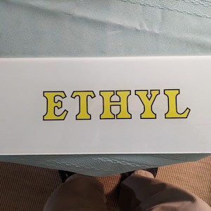 Szklana wkładka do dystrybutora paliwa, „ETHYL” w kolorze żółtym, z czarnym konturem. 5" X 12-11/16" (ok. 12,5 cm x 30,5 cm) – doskonały stan, bez uszkodzeń, wyrazista grafika. Numer faktury: 1301XA