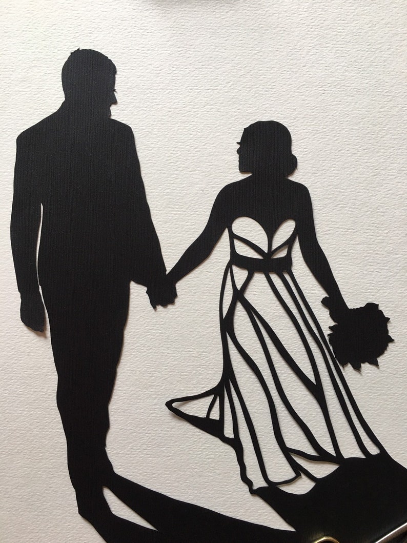 May include: Black silhouette of a couple holding hands. The woman is wearing a wedding dress with a bouquet of flowers. The man is wearing a suit.