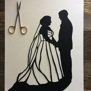 May include: A black paper silhouette of a bride and groom standing side by side. The bride is wearing a long gown with a veil and the groom is wearing a suit. The silhouette is cut out of white paper and is set against a white background.