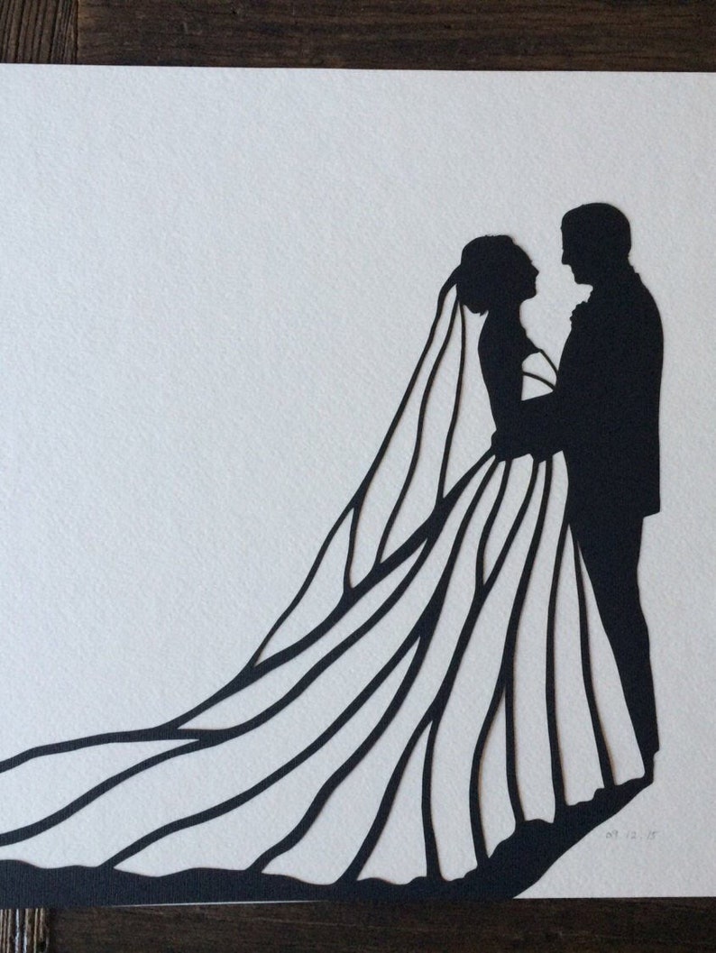 May include: Black silhouette paper cut-out of a bride and groom. The bride is wearing a long gown with a veil and the groom is wearing a suit. The couple is facing each other and holding hands.