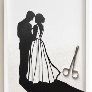 May include: A black paper silhouette of a bride and groom standing together, with a pair of silver scissors on a white background.