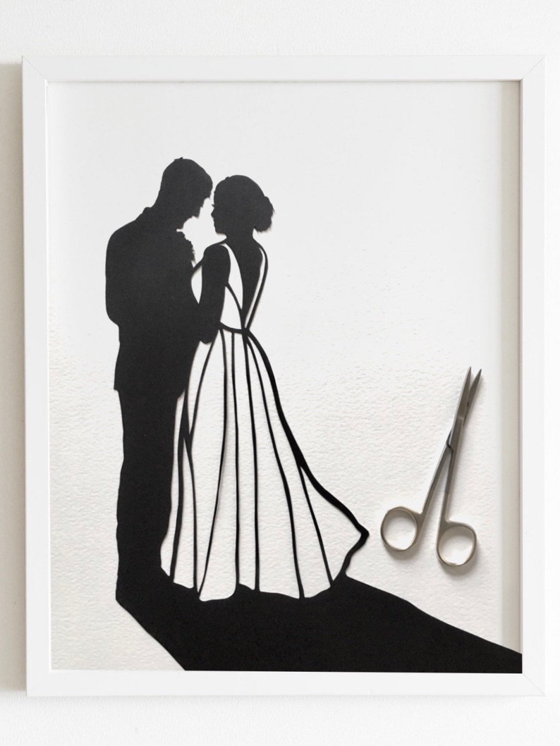 May include: A black paper silhouette of a bride and groom standing together, with a pair of silver scissors on a white background.