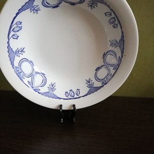 May include: A white ceramic bowl with a blue and white floral design around the rim. The bowl is on a dark brown surface.