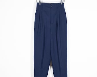 May include: A pair of dark blue high-waisted pants with pleats and cuffed hems hanging on a wooden hanger.