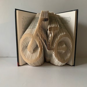 May include: A book with pages folded into the shape of a bicycle. The book is open and the bicycle is standing upright.