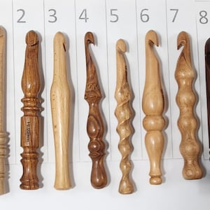 May include: Nine wooden crochet hooks of varying sizes and styles. The hooks are numbered 1 through 9. The hooks are made of different types of wood, including walnut, maple, and cherry. The hooks are all in focus and are arranged in a row.