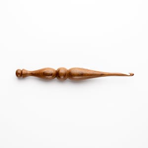 May include: A wooden crochet hook with a brown finish and a rounded handle.