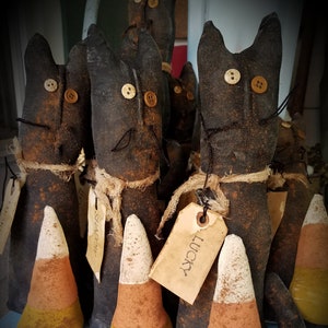 May include: Five black cat figurines with candy corn accents. Each cat has a tag with the word "Lucky" on it.