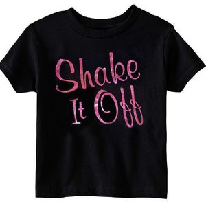 May include: Black t-shirt with a pink glitter design that says "Shake It Off".