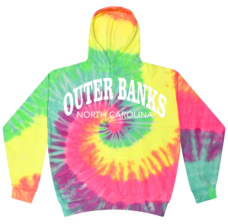 May include: A tie-dye hoodie in vibrant colors of yellow, green, pink, and orange. The hoodie features the text "Outer Banks North Carolina" in white block letters across the back. The design has a spiral pattern.