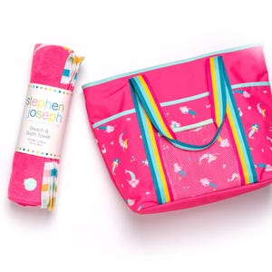 A pink beach towel and a pink tote bag with a rainbow pattern are placed next to each other on a white background.