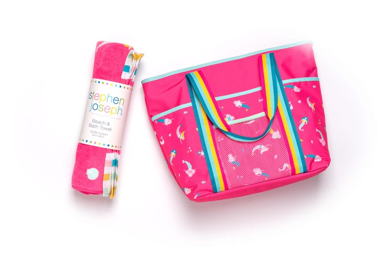 A pink beach towel and a pink tote bag with a rainbow pattern are placed next to each other on a white background.