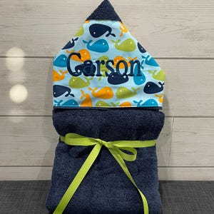 A blue towel with a yellow ribbon tied around it, placed on a wooden surface.
