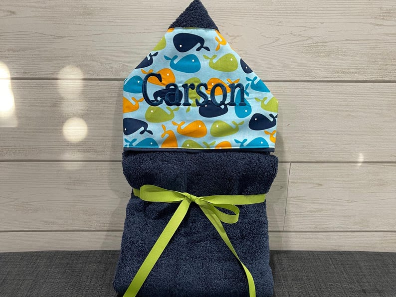 A blue towel with a yellow ribbon tied around it, placed on a wooden surface.
